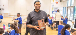 Chef Hugo holding his Catering Team Champion award in the school canteen
